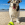 Chien blanc, brun et noir avec une balle de tennis KONG à la plage.