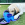 Een witte hond ligt in het gras te snuffelen aan een KONG snoepje.