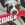 Un chien blanc et brun tenant un bâton KONG rouge dans sa gueule.