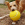A brown dog holing a large yellow KONG ball in his mouth.